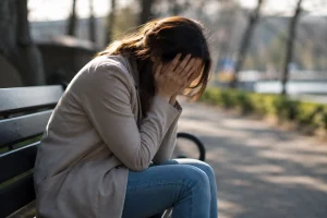 femme stressée assise sur un banc tête dans les mains pensées envahissantes fatigue mentale